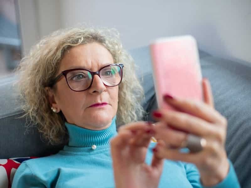 Sad woman scrolling on mobile phone.