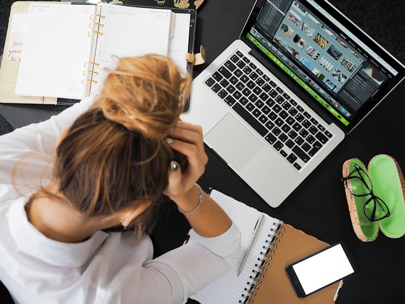 Woman sitting at a desk, with laptop open, trying to cope with returning to work after a holiday.