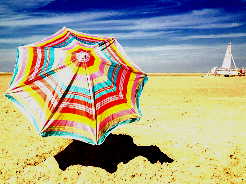 Brightly coloured umbrella on a beach.