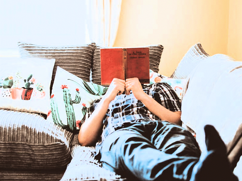 Blog-laziness A man lying on a sofa, reading.