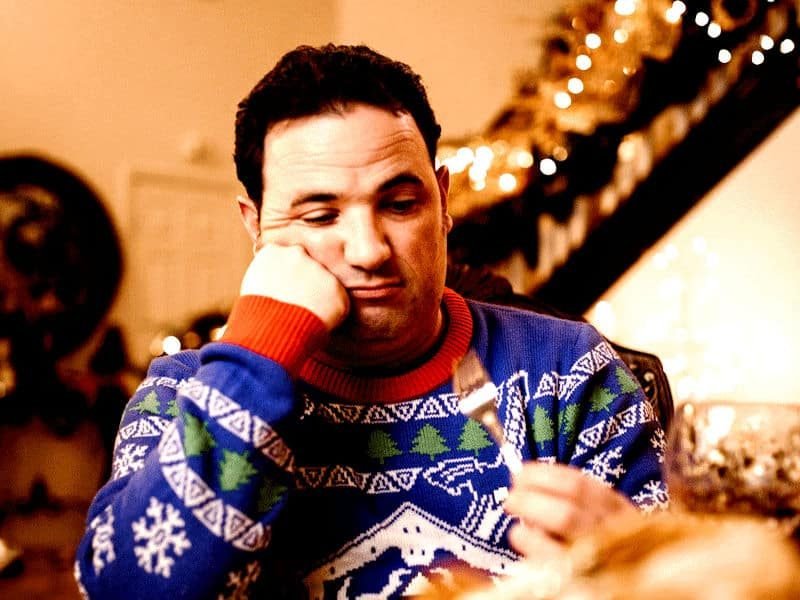 Man struggling with mental health issues at Christmas, sitting by himself and looking sad.