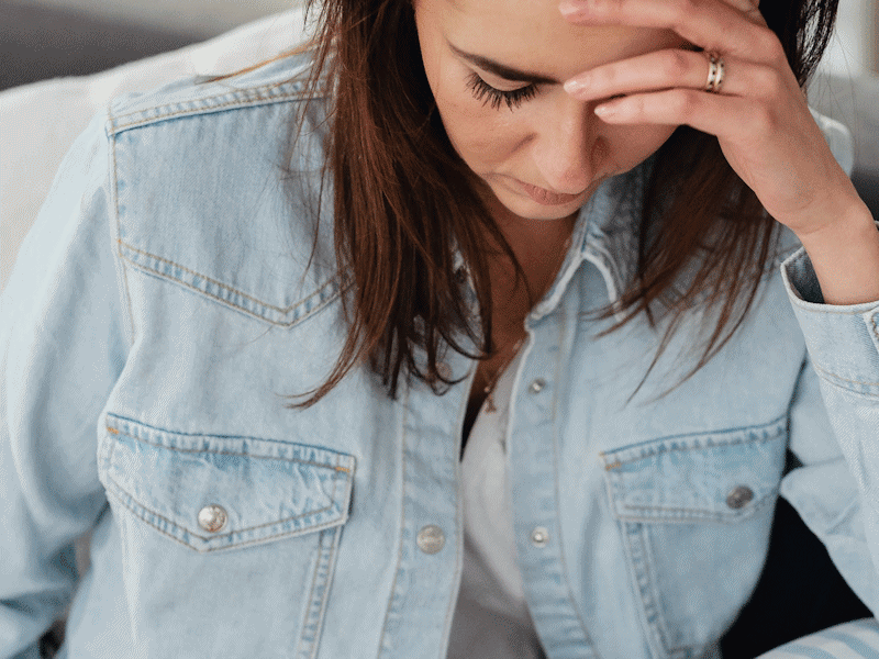 Depressed woman wearing blue denim jacket.